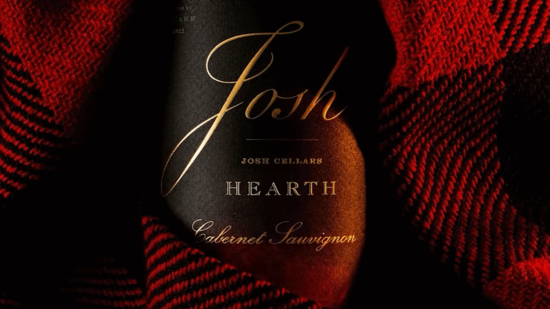 A bottle of Josh Cellars Earth Cabernet Sauvignon wine surrounded by red and black striped fabric.
