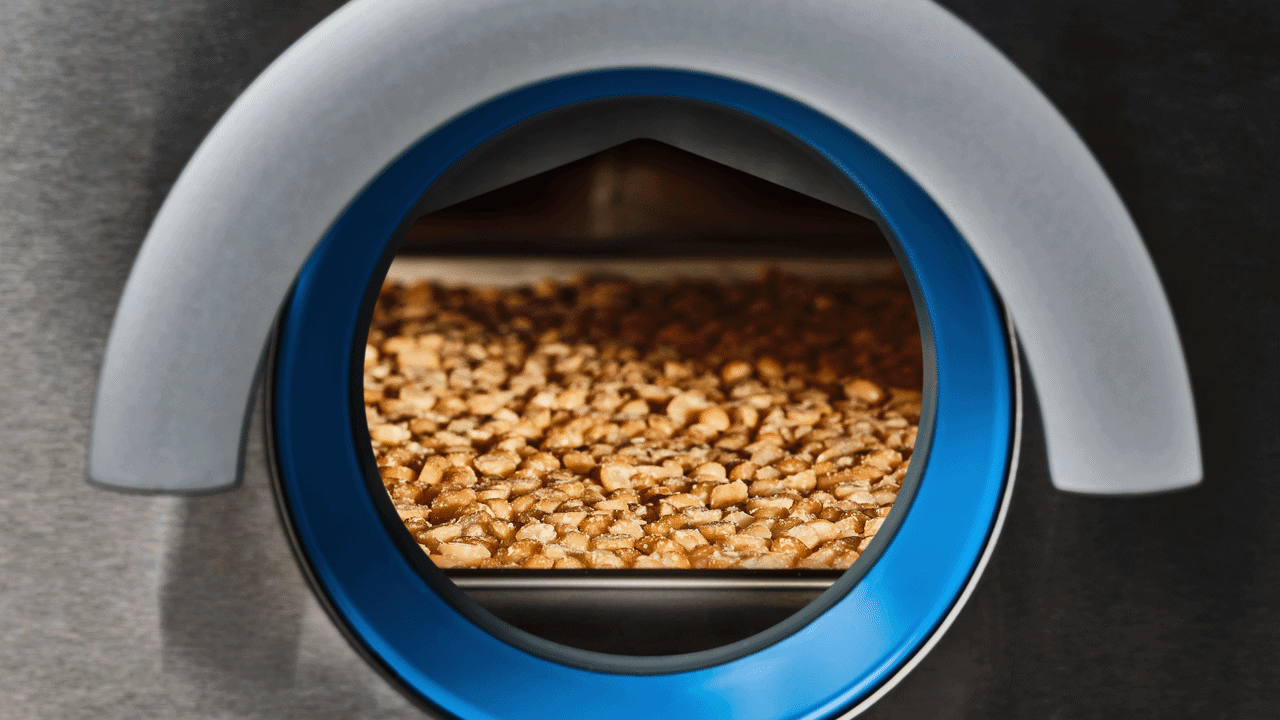 Close-up of a lab oven door with a tray of cooked ground meat inside.